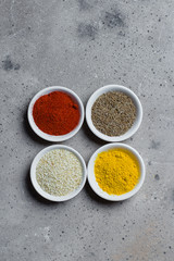 Spices in little white bowls on gray stone concrete background. Indian spice. Top view with space for text, copy space