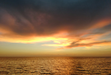Naklejka na ściany i meble a beautiful sunset at varakkal beach with dark shining colouds ocean coast reflection on the sea making a nature art horizon