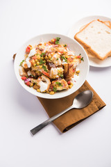 Bread chaat/chat is a yummy starter/appetizer from India, served in a bowl garnished with tomato, sev and coriander and masala. selective focus