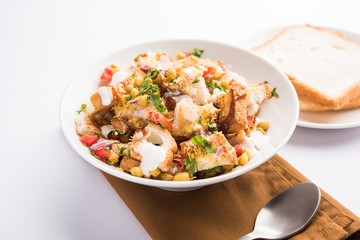 Bread chaat/chat is a yummy starter/appetizer from India, served in a bowl garnished with tomato, sev and coriander and masala. selective focus