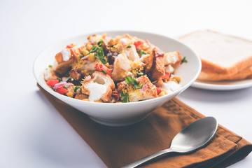 Bread chaat/chat is a yummy starter/appetizer from India, served in a bowl garnished with tomato, sev and coriander and masala. selective focus