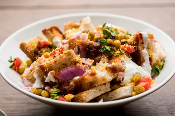 Bread chaat/chat is a yummy starter/appetizer from India, served in a bowl garnished with tomato, sev and coriander and masala. selective focus
