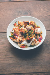 Bread chaat/chat is a yummy starter/appetizer from India, served in a bowl garnished with tomato, sev and coriander and masala. selective focus