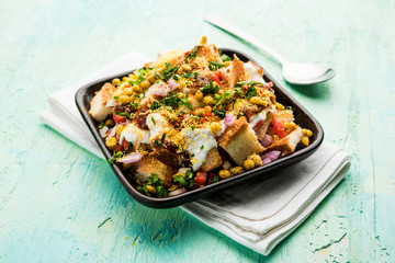Bread chaat/chat is a yummy starter/appetizer from India, served in a bowl garnished with tomato, sev and coriander and masala. selective focus