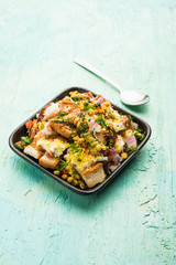 Bread chaat/chat is a yummy starter/appetizer from India, served in a bowl garnished with tomato, sev and coriander and masala. selective focus