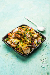 Bread chaat/chat is a yummy starter/appetizer from India, served in a bowl garnished with tomato, sev and coriander and masala. selective focus