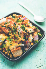 Bread chaat/chat is a yummy starter/appetizer from India, served in a bowl garnished with tomato, sev and coriander and masala. selective focus
