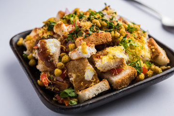 Bread chaat/chat is a yummy starter/appetizer from India, served in a bowl garnished with tomato, sev and coriander and masala. selective focus