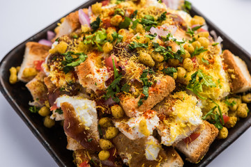 Bread chaat/chat is a yummy starter/appetizer from India, served in a bowl garnished with tomato, sev and coriander and masala. selective focus
