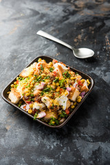 Bread chaat/chat is a yummy starter/appetizer from India, served in a bowl garnished with tomato, sev and coriander and masala. selective focus