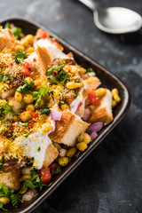 Bread chaat/chat is a yummy starter/appetizer from India, served in a bowl garnished with tomato, sev and coriander and masala. selective focus