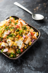 Bread chaat/chat is a yummy starter/appetizer from India, served in a bowl garnished with tomato, sev and coriander and masala. selective focus