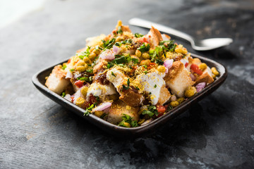Bread chaat/chat is a yummy starter/appetizer from India, served in a bowl garnished with tomato, sev and coriander and masala. selective focus