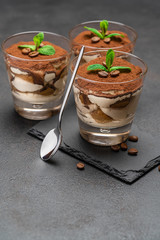 Classic tiramisu dessert in a glass on stone serving board on dark concrete background