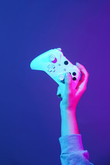 Hand with white gamepad on dark violet background.