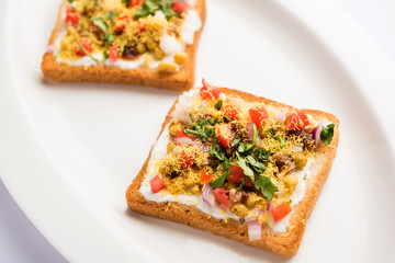 Bread ppadi chaat/chat is a yummy starter/appetizer from India, served in a plate garnished with tomato, sev and coriander and masala. selective focus