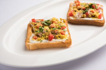 Bread ppadi chaat/chat is a yummy starter/appetizer from India, served in a plate garnished with tomato, sev and coriander and masala. selective focus
