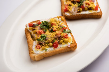 Bread ppadi chaat/chat is a yummy starter/appetizer from India, served in a plate garnished with tomato, sev and coriander and masala. selective focus