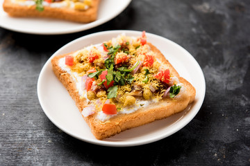 Bread ppadi chaat/chat is a yummy starter/appetizer from India, served in a plate garnished with tomato, sev and coriander and masala. selective focus