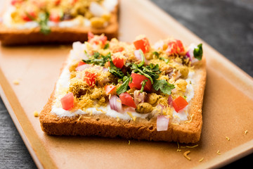Bread ppadi chaat/chat is a yummy starter/appetizer from India, served in a plate garnished with tomato, sev and coriander and masala. selective focus