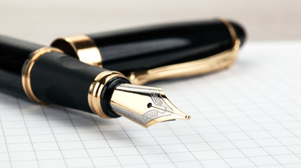 golden fountain pen on the notepad on a table