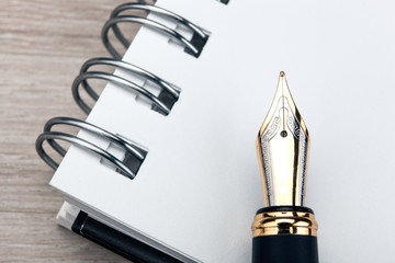 fountain pen on the notepad on a wooden table