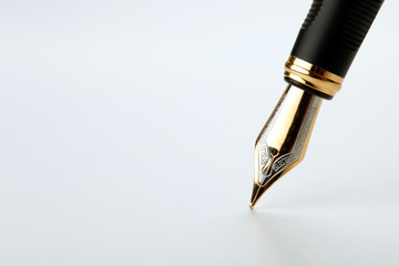 golden fountain pen writes on a white background