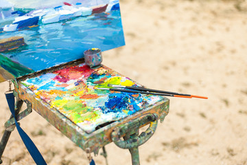 Colorful workplace of the artist with brushes and oil paints in the open air