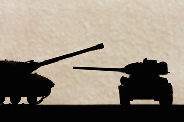 Silhouettes of scale models tanks on a light background. Toy. Background.