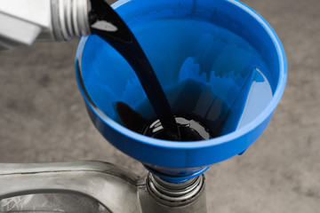 Pouring old black oil of  car engine from oil pan into bottle on top view lubrication used for...