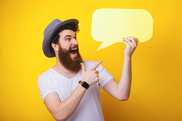 Look at this! Excited bearded man pointing at a speech bubble he is holding. Yellow theme.