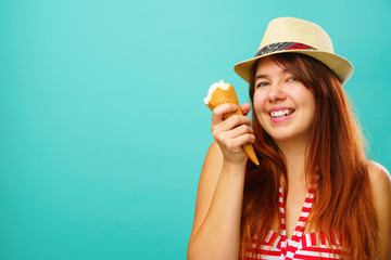Fototapeta na wymiar Woman wearing a a swimsuit and straw hat eats icecream from cup over colorful turquoise background