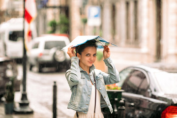 attractive woman in dress with map walks through the old city streets on rainy day