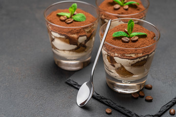 Classic tiramisu dessert in a glass on stone serving board on dark concrete background