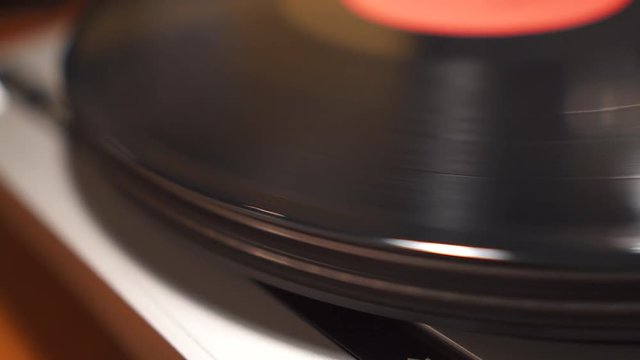 Vintage dusty vinyl is spinning fast on a silver record player closeup view