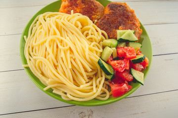 traditional dish consisting of spaghetti with chicken cutlets and vegetable salad.