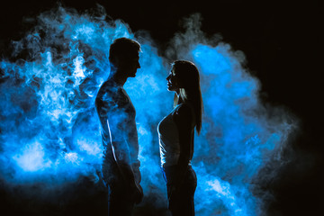 The couple standing in smoke on the dark background