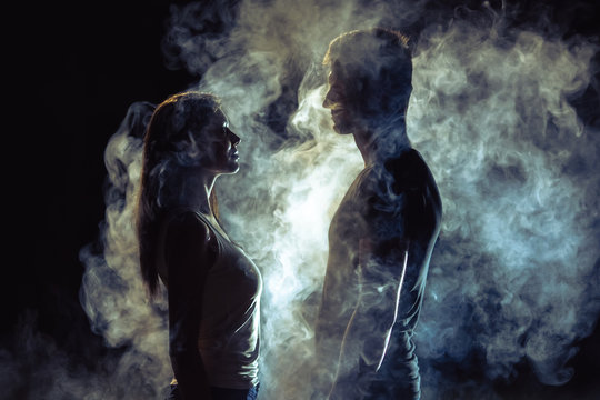 The man and woman standing in smoke on the dark background