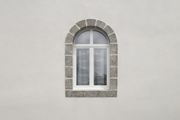 Modernes Bogenfenster aus weißem PVC mit Granitfenstereinfassung frontal mit Textfreiraum in weißer Fassade 