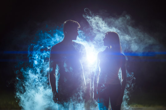The man and woman standing in the smoke on a bright light background