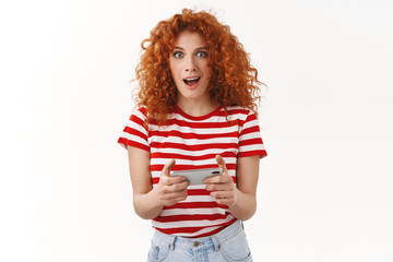 Amused excited good-looking female redhead geek attractive woman playing cool new app smartphone...