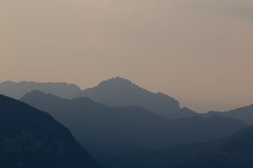 Natural patterns: layers of mountains in a foggy soft light at sunset. Garda Lake, Italy. Artistic,...