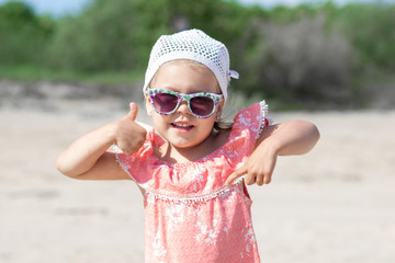 Portrait of joyful smiling and happy little girl in sunglasses  playing the ape