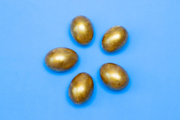 Golden eggs on a blue background. Concept of wealth