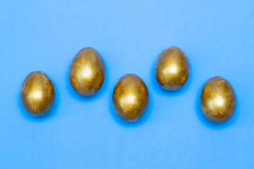 Golden eggs on a blue background. Concept of wealth