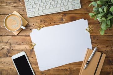 School paper with coffee cup, smartphone and plant on wooden table. Top view from above