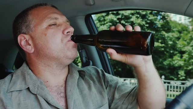 The driver drinks alcohol at the wheel. Dangerous illegal behavior concept
