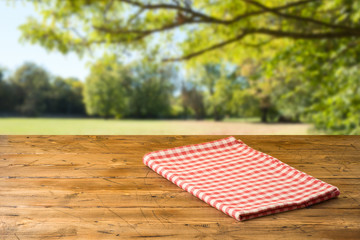 Empty wooden table with tablecloth over autumn nature park background