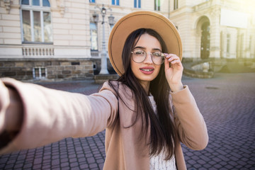 Closeup selfie-portrait student of attractive girl in sunglasses smile in city.