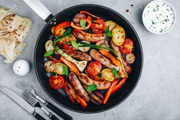 Grilled vegetables and sausages in cast iron pan